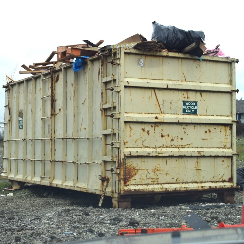 Large roll-off dumpster filled with wood and construction debris for dumpster rental services near me