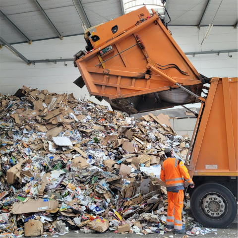 Waste collection truck unloading mixed commercial debris at a disposal facility for dumpster rental services near me