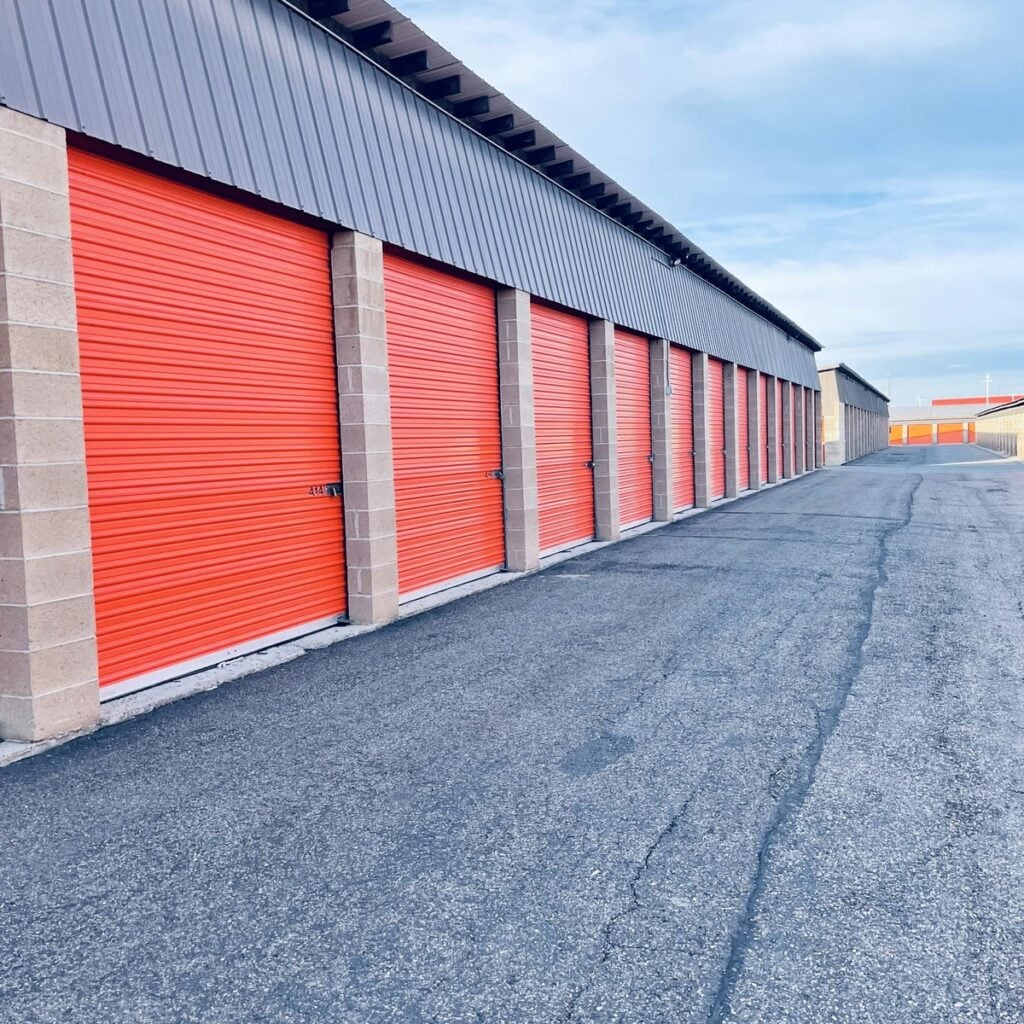 Row of commercial storage units with orange roll-up doors for storage services near me